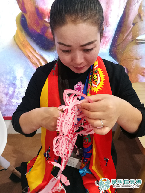 陕西靖边展区的剪纸师傅正在剪纸。