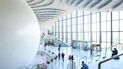 天津滨海新区图书馆内，读者坐在阶梯上看书。韩寒摄/光明图片