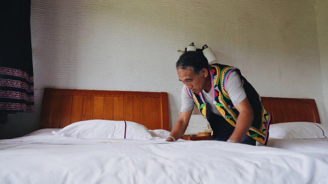 Li Shikai makes a bed at his homestay to greet visitors. Luo Caiwen/CGTN