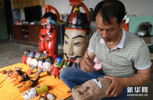 方文展在为一个毛南族傩面上涂料