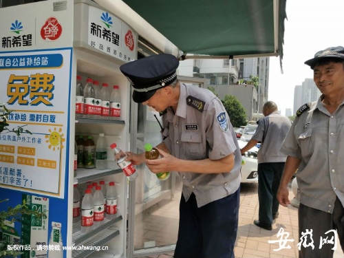 几名保安在合肥市南七街道丁香社区的爱心冰箱里取水。