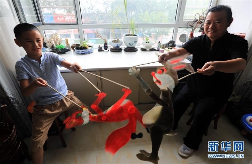 李卫与外孙一起表演皮影(7月11日摄)。 李卫与外孙一起表演皮影(7月11日摄)。