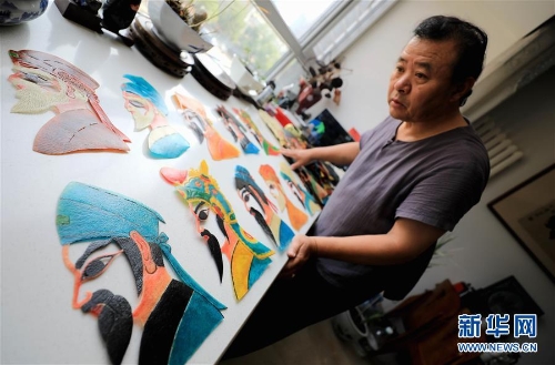 李卫展示自己制作的“济南名人脸谱”系列的皮影人偶(7月5日摄)。 李卫展示自己制作的“济南名人脸谱”系列的皮影人偶(7月5日摄)。
