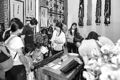 观众在非遗展区体验古琴弹奏 陈德欢 摄 观众在非遗展区体验古琴弹奏 陈德欢 摄