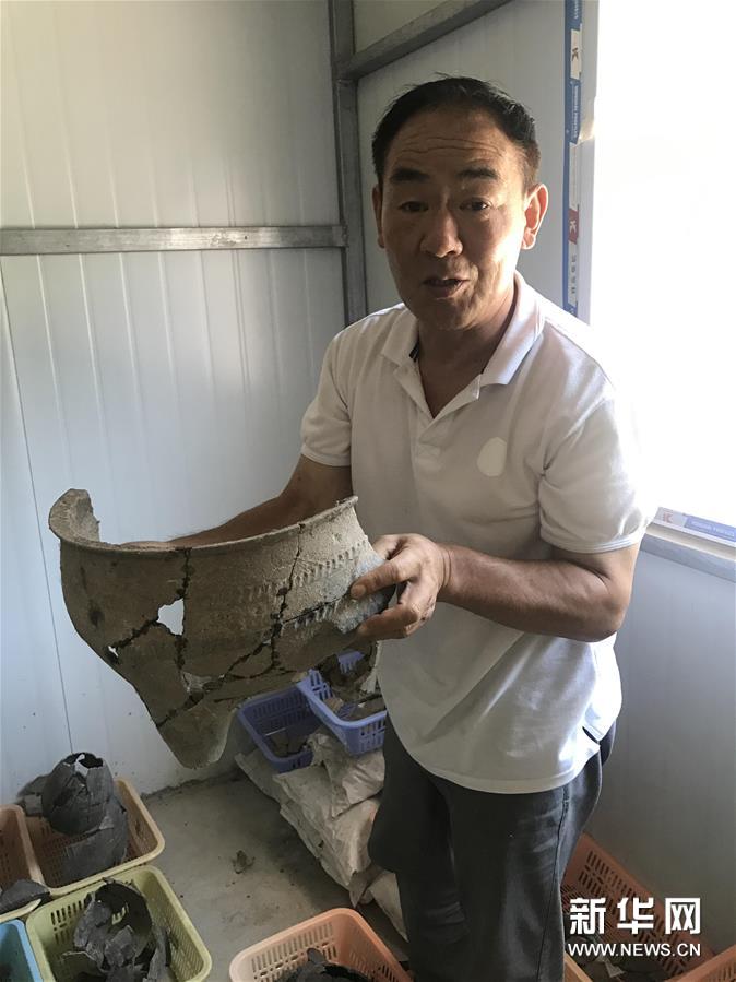 考古人员张官狮介绍陶寺遗址出土文物（8月13日摄）。