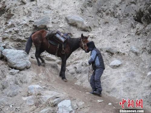 图为居马泰•俄白克行走在崎岖险峻的道路上。 刘灵波 摄