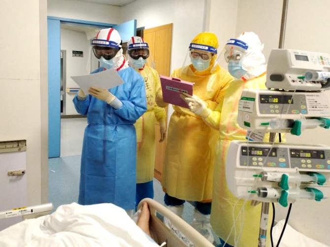 2月11日,在武汉同济医院中法新城院区ICU病房内,来自北京协和医院的医护人员在病床旁查房交班。