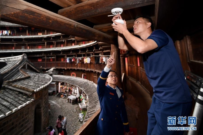 12月10日,福建省南靖县土楼景区专职消防队员(右)在土楼怀远楼内检查智能烟感探测器。 12月10日,福建省南靖县土楼景区专职消防队员(右)在土楼怀远楼内检查智能烟感探测器。
