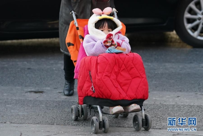 12月29日,在北京朝阳区青年路和朝阳北路路口,一名小朋友坐在盖着厚厚衣服的童车上。当日,入冬最强寒潮来袭,多地迎来今冬最寒冷天气。新华社记者鞠焕宗 摄 12月29日,在北京朝阳区青年路和朝阳北路路口,一名小朋友坐在盖着厚厚衣服的童车上。当日,入冬最强寒潮来袭,多地迎来今冬最寒冷天气。新华社记者鞠焕宗 摄