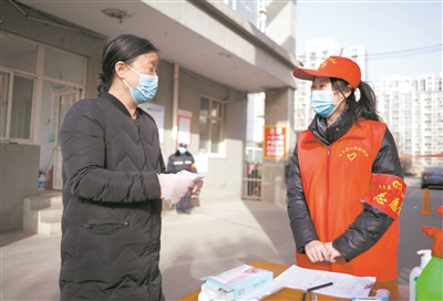 1月11日，承德护理职业学院返乡学生赵梦鸽（右）在河北省邢台市内丘县一小区门口核实群众信息。当前，河北省疫情防控形势严峻，内丘县有300余名返乡大学生志愿者深入社区、村庄、执勤卡点，开展信息登记、物资搬运、食品代购等抗疫志愿服务工作。刘继东 摄