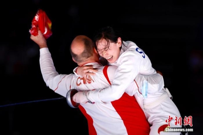 7月24日晚,东京奥运会女子重剑个人赛结束了决赛的较量,中国选手孙一文以11:10战胜罗马尼亚选手波佩斯库,夺得冠军。这是中国体育代表团在本届奥运会的第三枚金牌。图为孙一文夺冠后和团队成员一起庆祝。<a target='_blank' href='http://www.chinanews.com/'>中新社</a>记者 富田 摄 点击进入下一页