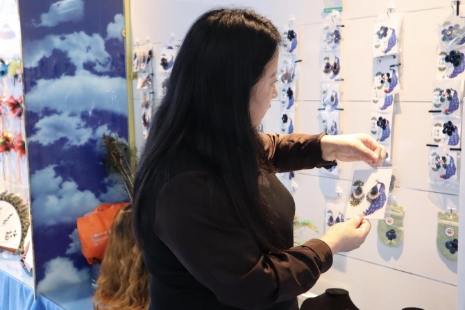 (周海燕在展示孔雀羽毛工艺品制作 央视网记者 王静远 摄)