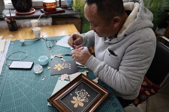 (手艺师傅正在制作树皮画 央视网记者 王静远 摄)