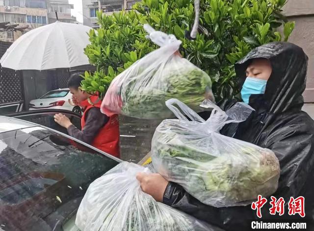 长宁区建宁居民区党总支书记马开骏(右)冒雨搬运物资 受访者供图
