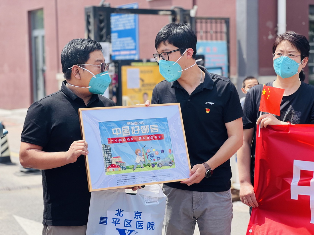 张旭(左一)康复后回到小区,收到了一幅主题为“中国好邻居”的手工艺品礼物(5月18日摄)。新华社发(周紫欣 摄)