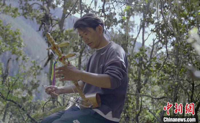 图为白马扎史在巡护森林时拉起弦子。　张历　摄