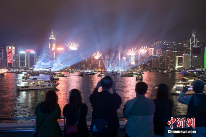 2023年1月1日零时，维多利亚港两岸灯光璀璨，绽放烟花，香港迎来新的一年。图为市民在海滨倒数迎新年。 中新社记者 陈永诺 摄