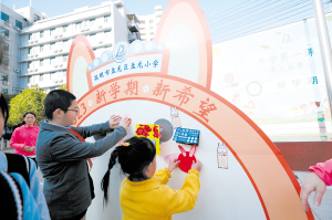 盘龙小学的学生将心愿卡粘贴在展板上。记者李海曦摄