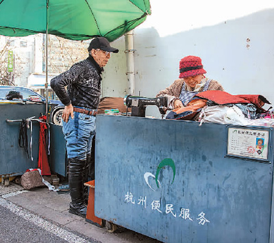 浙江省杭州市让“小修小补”的便民店铺规范有序回归百姓生活。图为西湖区北山街道便民服务摊位，裁缝师（右）为社区居民修补衣物。  新华社记者 江 汉摄