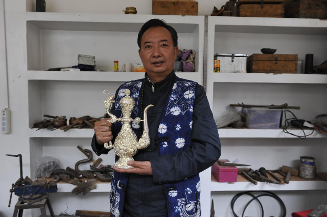 寸发标，从事银器制作40年，手持九龙壶.png