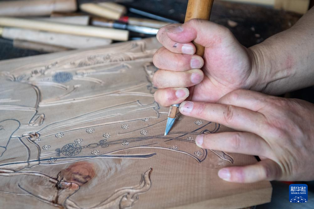 8月10日，梁平木版年画代表性传承人徐家辉在为学员演示雕版工序。