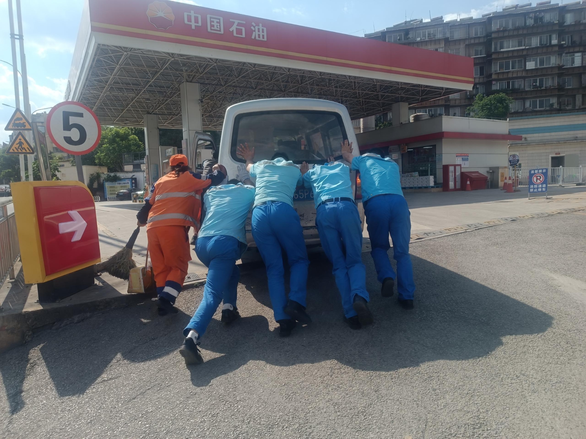 加油站员工和环卫工人帮忙为车辆抛锚顾客推车进站加油 加油站员工和环卫工人帮忙为车辆抛锚顾客推车进站加油