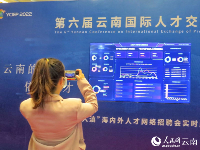 【7】第六届云南国际人才交流会上，一名求职者正在拍摄”引才入滇“海内外人才网络招聘会实时数据大屏。（人民网-刘怡摄）