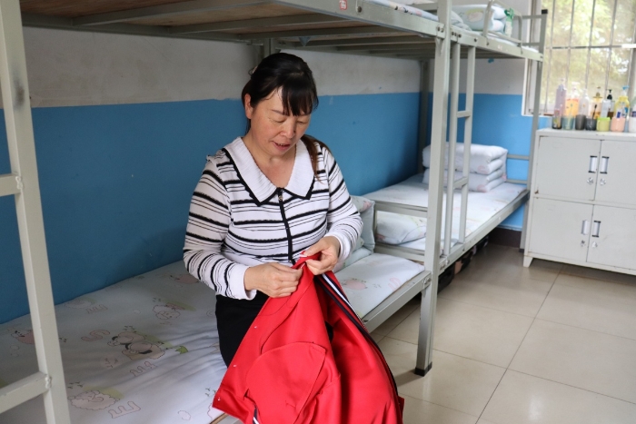 生活老师给学生衣服钉扣子